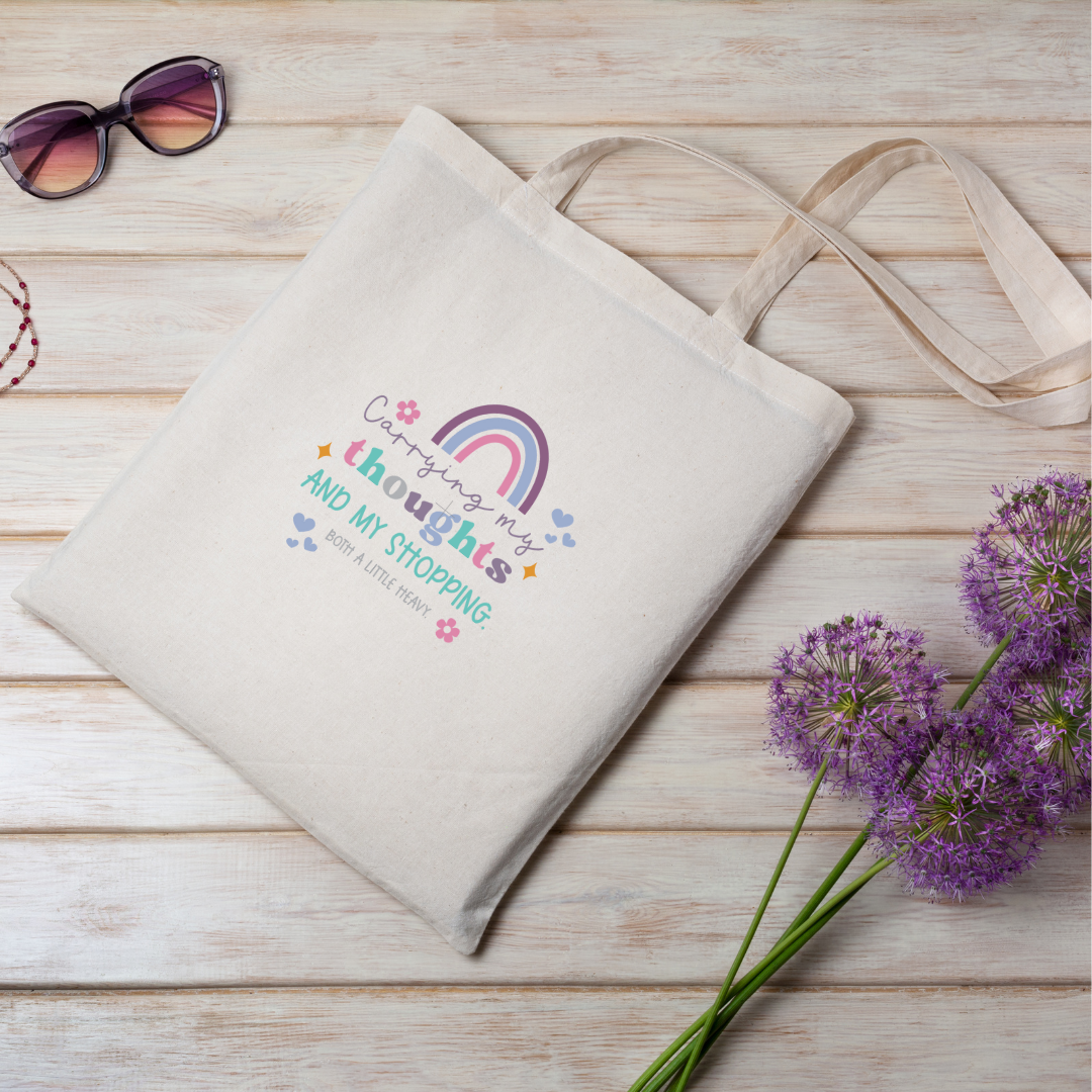 Natural Cream cotton tote bag with shoulder straps and rainbow design with the wording 'Carrying my thoughts and my shopping. Both a little heavy'.